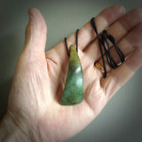 This photo shows a beautiful large flower jade drop. It is hand carved from a piece of New Zealand pounamu, with fascinating orange and green inclusions throughout the stone. We have this on a black coloured, adjustable four plait cord. We ship this worldwide with an express courier service. Postage is free.