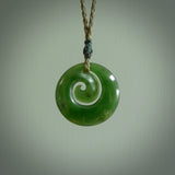 Hand carved New Zealand jade koru pendant. Delivered to you on a hand plaited manuka green cord which is adjustable. Free delivery worldwide.