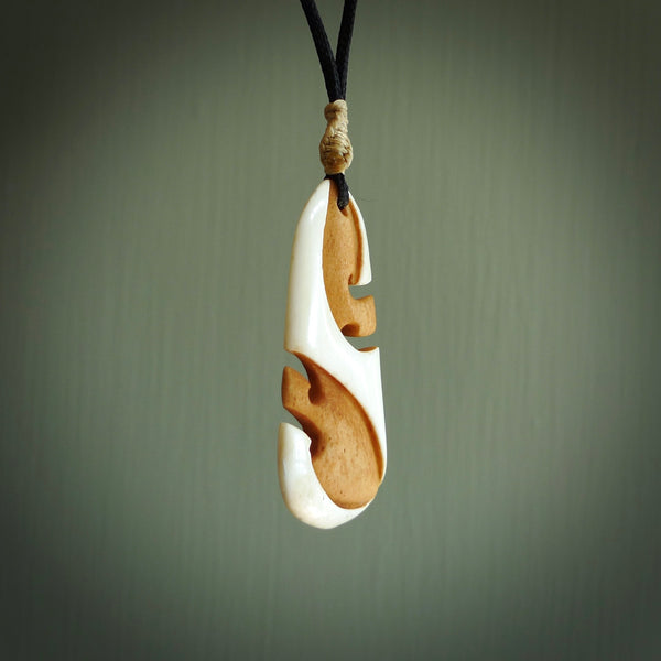 A hand carved bone toki with double koru, intricate pendant. The cord is a black colour and is adjustable. A medium sized hand made toki with koru necklace by New Zealand artist Tonijae Brockway. Tonijae has stained parts of the bone which really add to the dimension of this pendant. One off work of art to wear.
