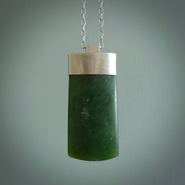This picture shows a hand carved jade toki, drop pendant with sterling silver cap and chain. The jade is a very dark green with a shimmer in the stone. It is suspended from a sterling silver clasp and we supply a sterling silver chain. Delivery is free worldwide.