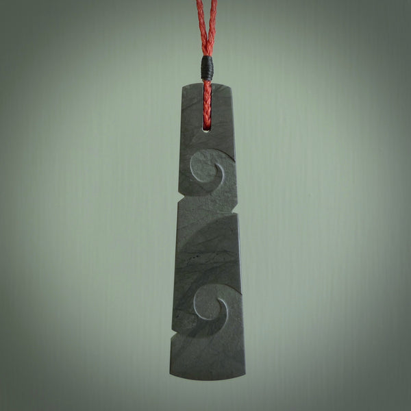 Hand carved New Zealand Argillite Toki with double koru by Rueben Tipene. We provide this large toki on an adjustable cord and ship to you in a kete pouch with Express Courier. This is a one off pendant that once sold will be removed from our site.