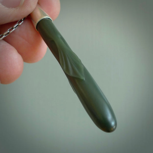 This picture shows a hand carved Inanga Pounamu, jade drop pendant with sterling silver cap and chain. The jade is a very dark green with a shimmer of light blue tones in the stone. It is suspended from a sterling silver clasp and we supply a sterling silver chain. Delivery is free worldwide.