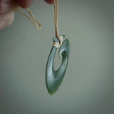 This picture shows a jade hook pendant, also called a hei-matau, carved for us in New Zealand jade. The jade is a wonderful deep mint green pounamu. This is a rare jade loved and valued for its distinctive colour. The carver is Ric Moor - and this is a beautiful example of his work. The cord is a four-plait, adjustable beige coloured necklace.