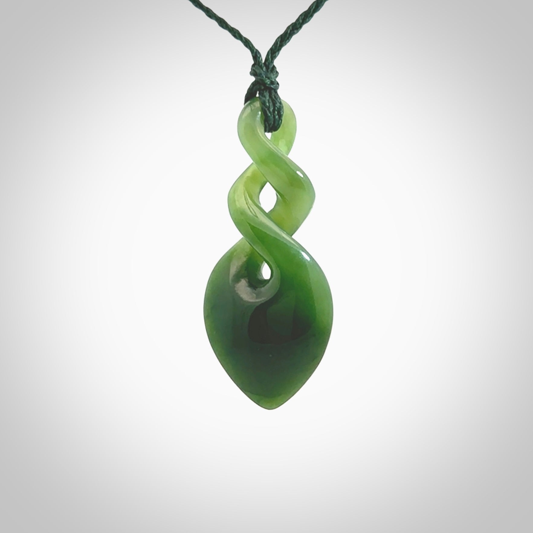 Hand carved New Zealand jade twist pendant. Carved in New Zealand by NZ Pacific. Unique double twist jewellery for sale online. Provided with an adjustable manuka green cord.