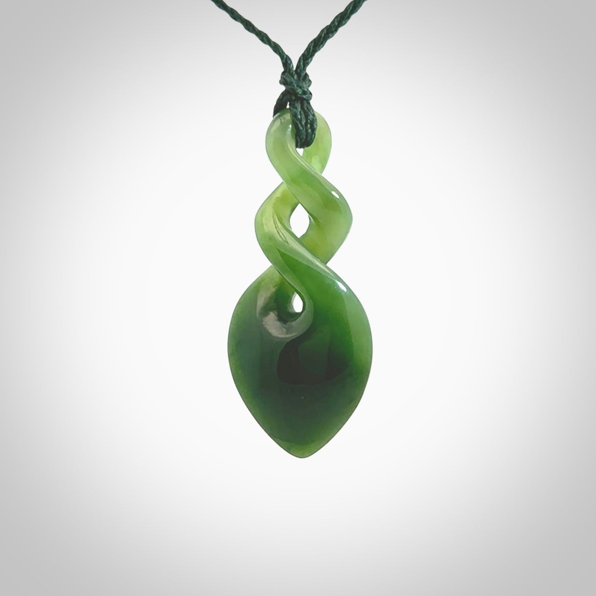 Hand carved New Zealand jade twist pendant. Carved in New Zealand by NZ Pacific. Unique double twist jewellery for sale online. Provided with an adjustable manuka green cord.