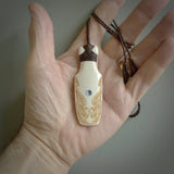 Hand carved engraved bone toki necklace hand made here in New Zealand. One only artistic toki pendant with hand plaited dark brown adjustable cord. Shipped to you with Express Courier. Stand out toki pendant for men and women. Bone Toki with engraved spiral on the back and paua shell insert on the front.