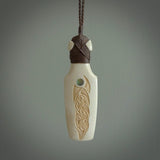 Hand carved engraved bone toki necklace hand made here in New Zealand. One only artistic toki pendant with hand plaited dark brown adjustable cord. Shipped to you with Express Courier. Stand out toki pendant for men and women. Bone Toki with engraved spiral on the back and paua shell insert on the front.
