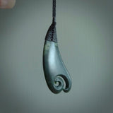 A hand carved large sized drop pendant with a koru carved into the front face. This is a piece of genuine jade jewellery, hand carved by Ric Moor. He has used New Zealand jade and has utilised his experience and carving skill to highlight the natural beauty of the stone. Delivered worldwide, postage is included in the price.