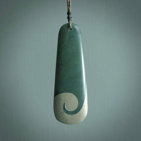 This photo shows a large jade drop shaped pendant. It a a lovely, colourful Inanga jade. The cord is a four plait green and tan colour and is adjustable in length. One only large, contemporary drop necklace from Jade, by Rueben Tipene.
