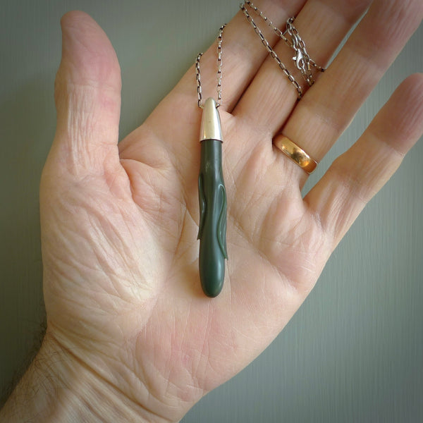 This picture shows a hand carved Inanga Pounamu, jade drop pendant with sterling silver cap and chain. The jade is a very dark green with a shimmer of light blue tones in the stone. It is suspended from a sterling silver clasp and we supply a sterling silver chain. Delivery is free worldwide.