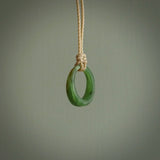 This piece is a oval round, ring pendant. It was carved for us by Ric Moor from a lovely light and milky green piece of New Zealand jade. It is suspended on a beige coloured braided cord that is length adjustable.