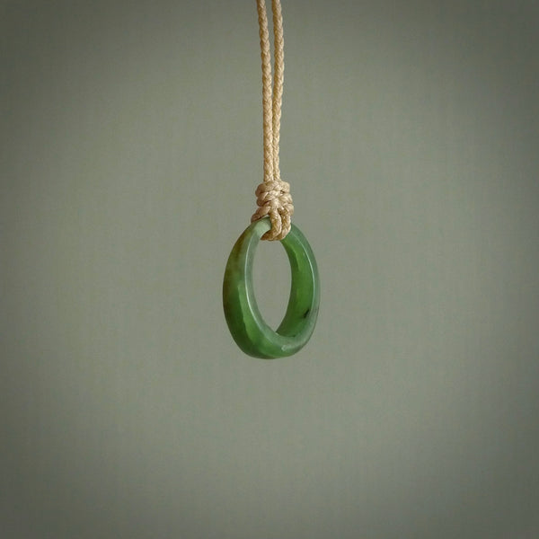 This piece is a oval round, ring pendant. It was carved for us by Ric Moor from a lovely light and milky green piece of New Zealand jade. It is suspended on a beige coloured braided cord that is length adjustable.