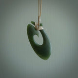This picture shows a jade hook pendant, also called a hei-matau, carved for us in New Zealand jade. The jade is a wonderful deep mint green pounamu. This is a rare jade loved and valued for its distinctive colour. The carver is Ric Moor - and this is a beautiful example of his work. The cord is a four-plait, adjustable beige coloured necklace.