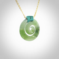 Hand carved British Columbian jade koru pendant. Delivered to you on a hand plaited oat coloured cord which is adjustable. Free delivery worldwide.