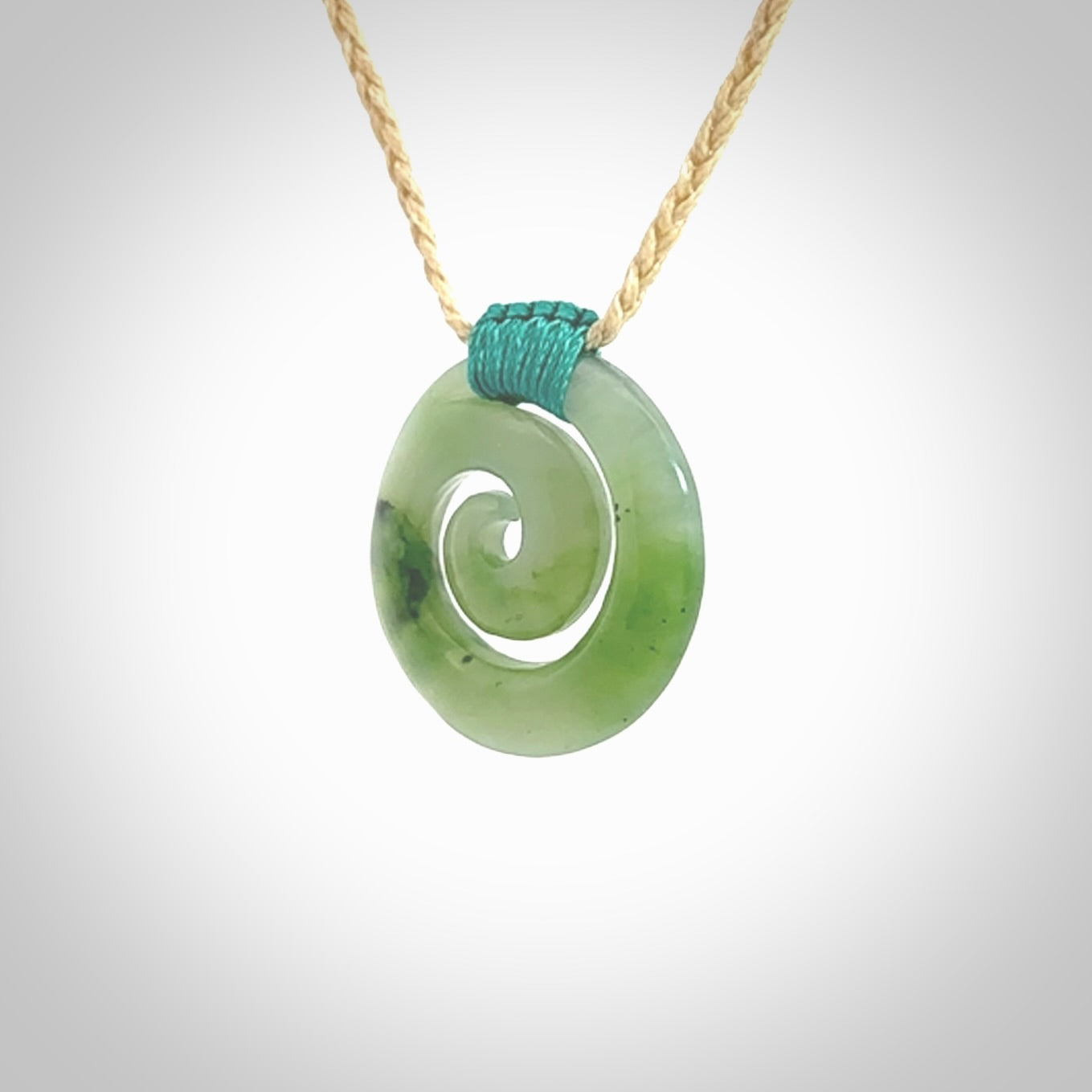 Hand carved British Columbian jade koru pendant. Delivered to you on a hand plaited oat coloured cord which is adjustable. Free delivery worldwide.