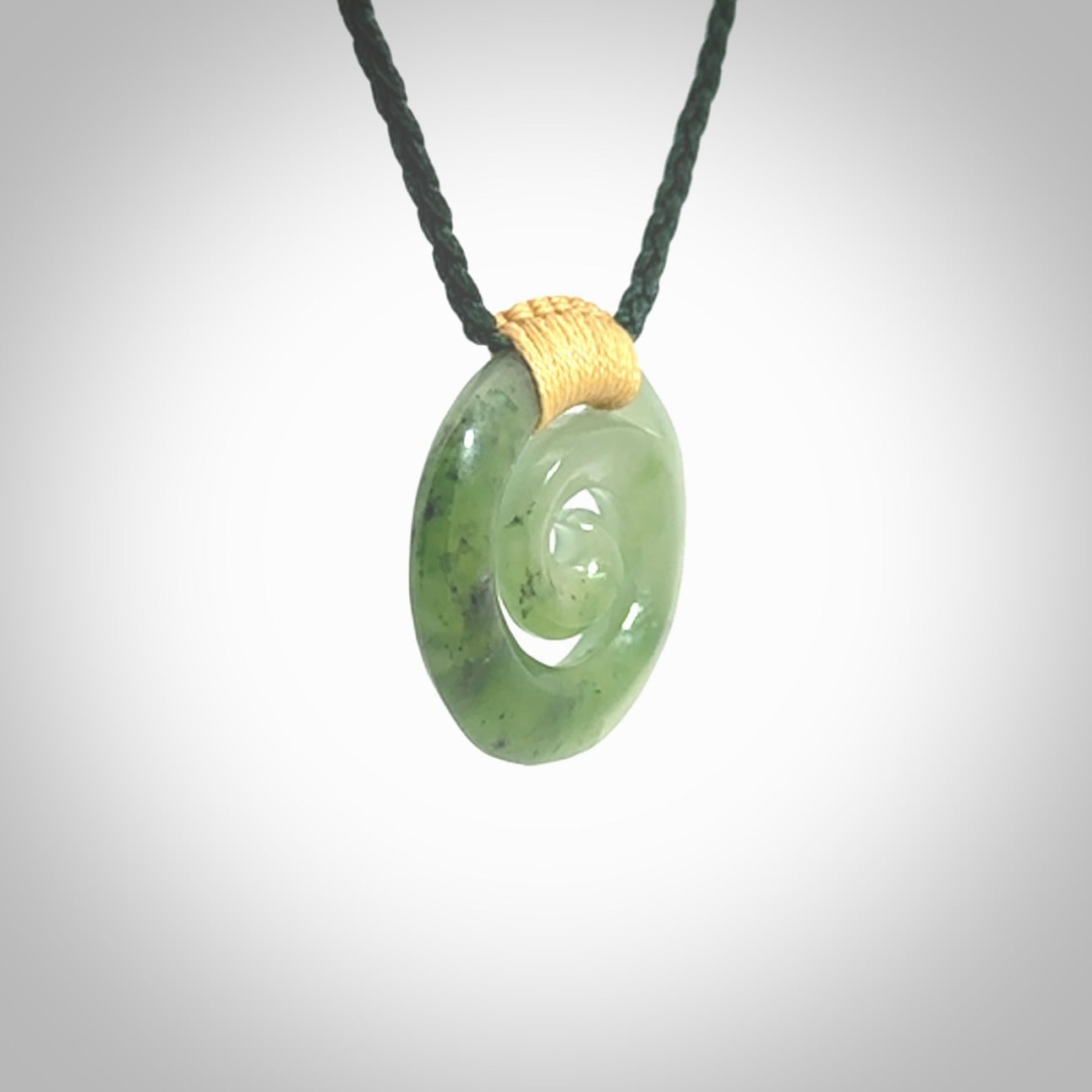 Hand carved British Columbian jade koru pendant. Delivered to you on a hand plaited manuka green cord which is adjustable. Free delivery worldwide.