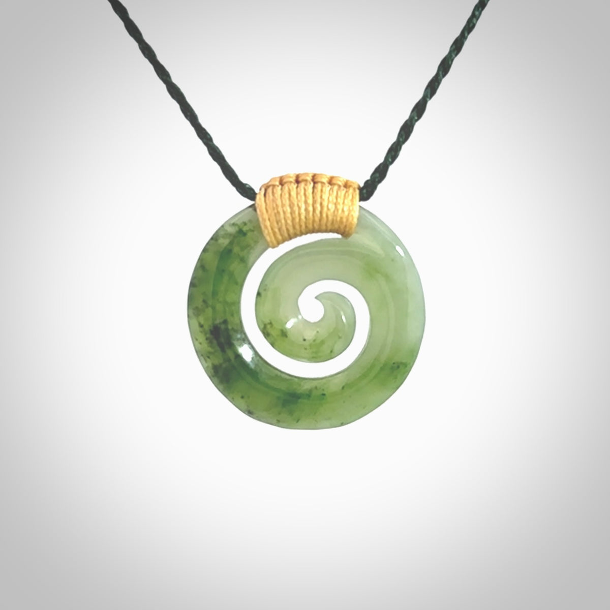 Hand carved British Columbian jade koru pendant. Delivered to you on a hand plaited manuka green cord which is adjustable. Free delivery worldwide.