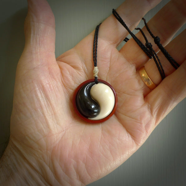 A hand carved and intricate yin and yang pendant made for us by Yuri Terenyi. This is a beautiful little piece and is emblematic of the well known and loved YIN & YANG design. It is carved from bone and buffalo horn. We have two available - one is suspended from an Ice White cord with a black floret and the other is suspended from an Black cord with Ice white floret. The necklace is adjustable.