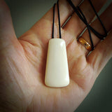 A hand carved unbound bone toki pendant. The cord is a black colour and is adjustable. Medium and large, hand made toki necklaces by New Zealand artist Kerry Thompson. One off work of art to wear.
