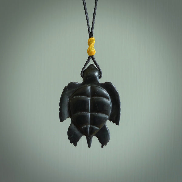 This picture shows a hand carved black jade turtle pendant. It is polished to a soft shine and has quite a lot of detail carved into the jade. The cord is a hand plaited black, waxed polyester. Carved by NZ Pacific.
