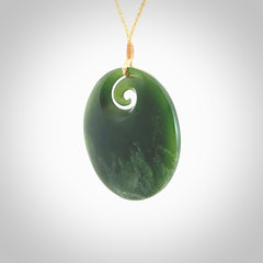 This picture shows a large hand carved jade koru pendant. It is a darker green colour which is quite translucent where the jade is thin. Although a large piece, it is a wonderful, delicate piece of jewellery. The cord is hand plaited and adjustable so that you can position the pendant where it suits you best. This koru was carved for us by Ric Moor. Delivery is free worldwide.