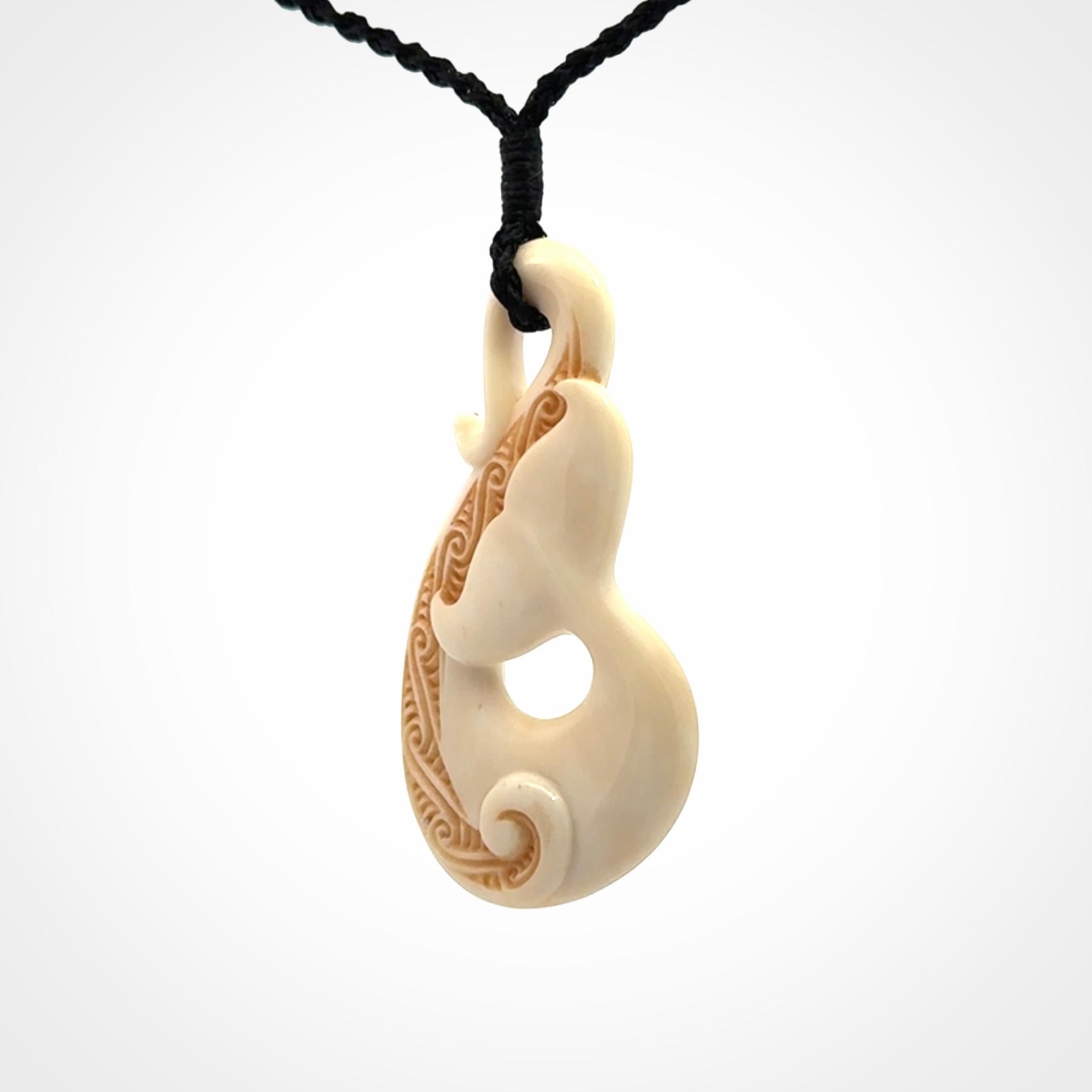 Hand carved Bone Whale Tail pendant by Andrew Doughty. Whale tail pendant by Andrew Doughty with engraving in it. Beautiful unisex necklace hand carved in New Zealand, delivered in a woven kete pouch. Provided with an adjustable beige cord.