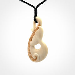 Hand carved Bone Whale Tail pendant by Andrew Doughty. Whale tail pendant by Andrew Doughty with engraving in it. Beautiful unisex necklace hand carved in New Zealand, delivered in a woven kete pouch. Provided with an adjustable beige cord.