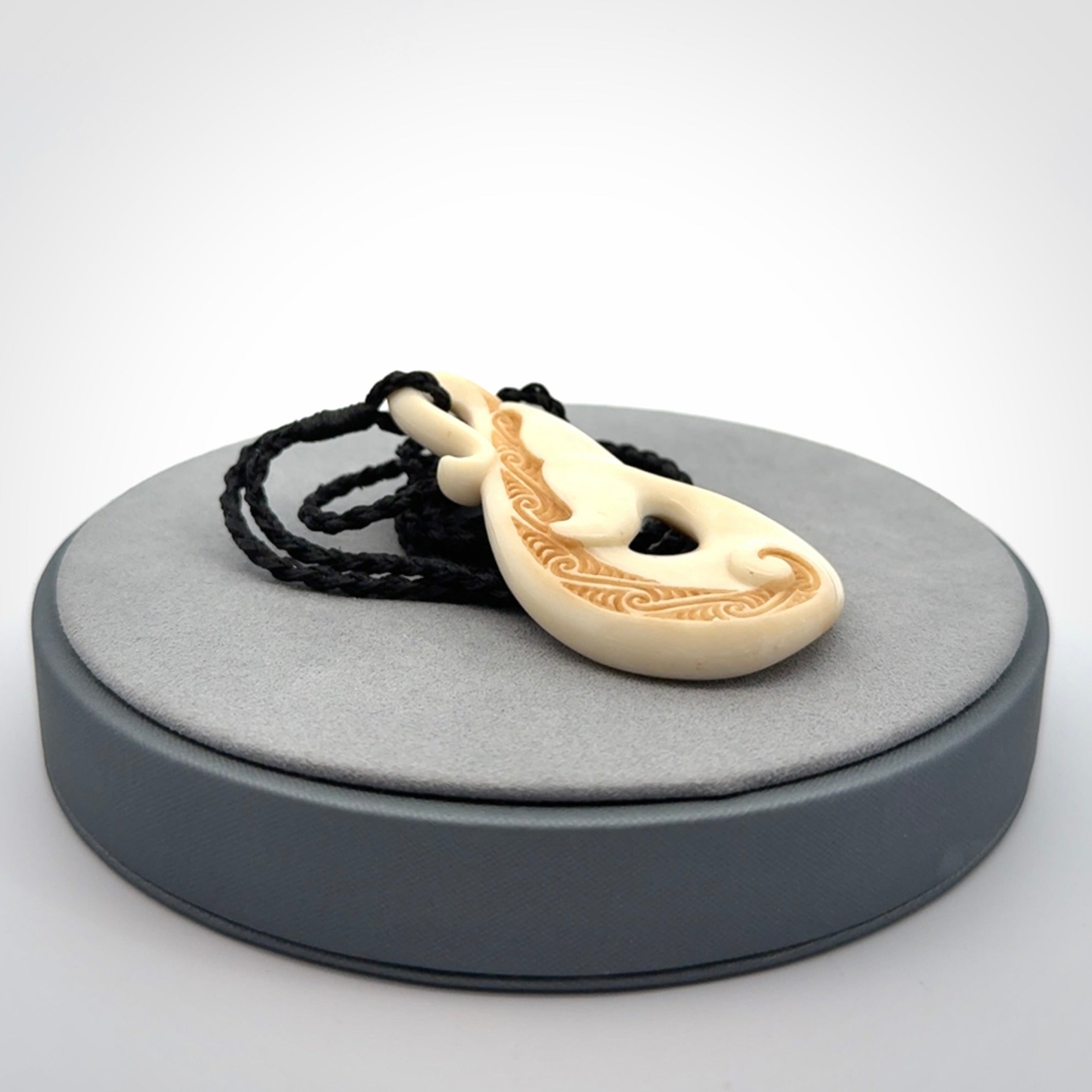 Hand carved Bone Whale Tail pendant by Andrew Doughty. Whale tail pendant by Andrew Doughty with engraving in it. Beautiful unisex necklace hand carved in New Zealand, delivered in a woven kete pouch. Provided with an adjustable beige cord.