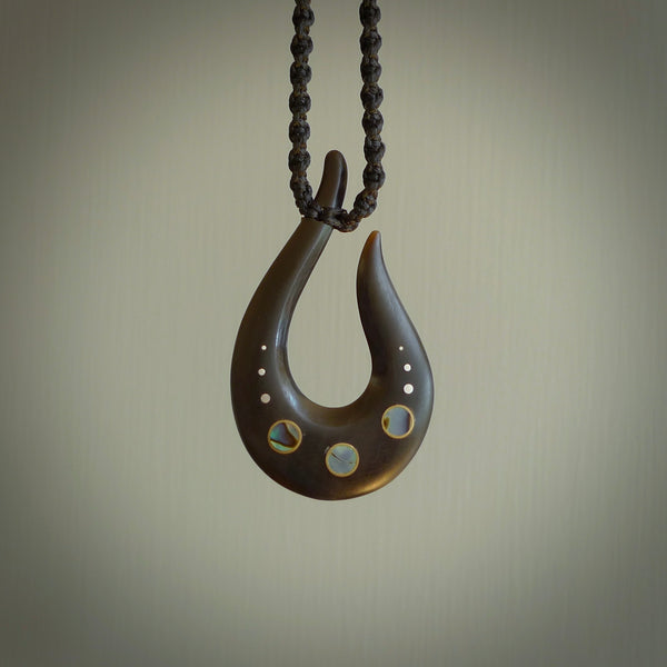 This photo shows a medium horn matau, hook pendant hand carved from horn with premium nz paua shell, Australian Golden and Tahitian Black Mother of Pearl alongside; brass, copper and silver. This is a stand out one off necklace for those who appreciate art to wear. It is provided with a cord in black that is a fixed length with Paua Shell Toggle. We ship this piece worldwide and shipping is included in the price.