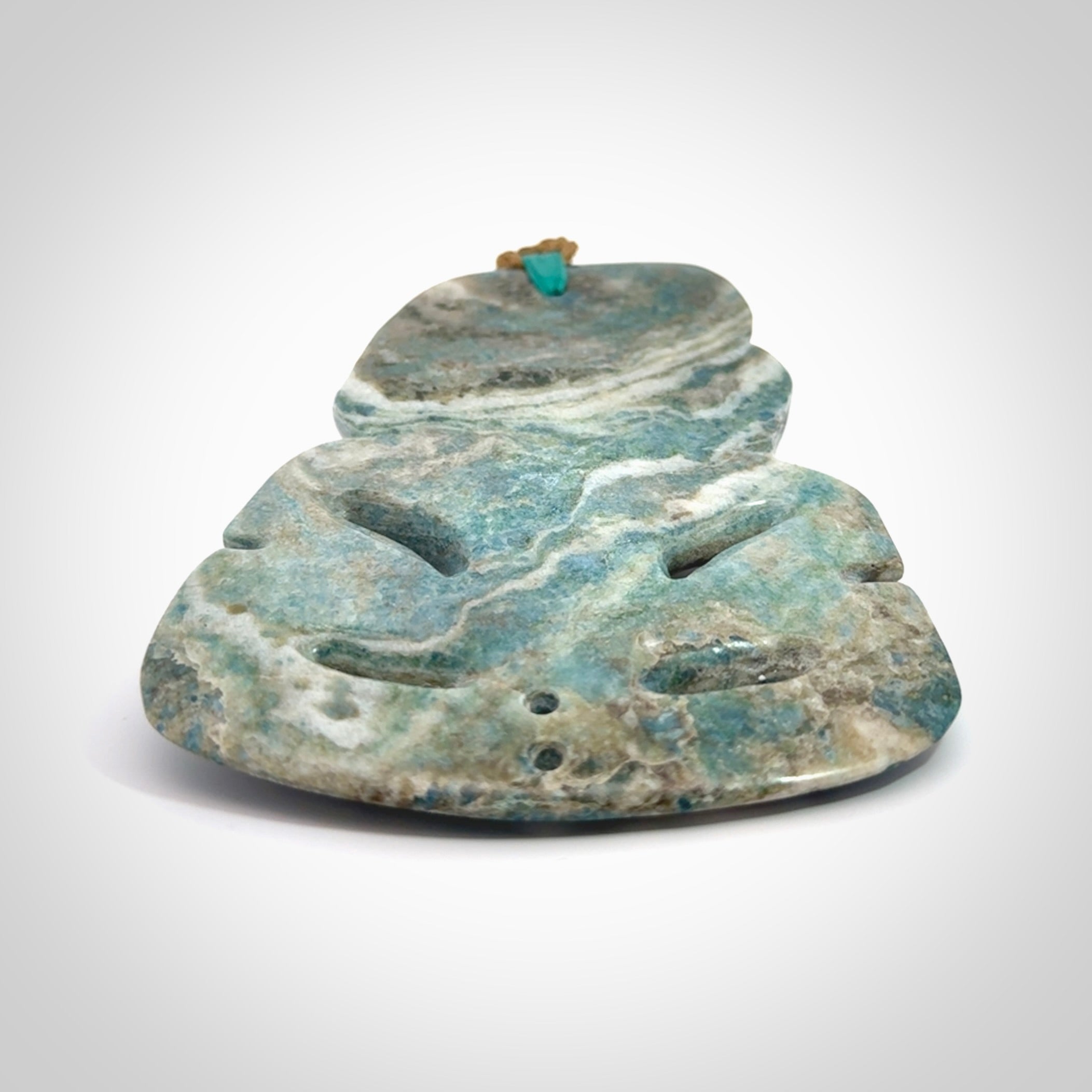 This photo shows a large hand carved Aotea stone Tiki pendant. It is a very light blue colour with pāua shell insert eyes. The cord is a thick camel colour and is length adjustable