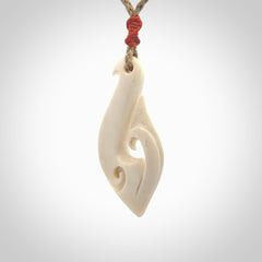 Hand carved bone hook pendant hand made by Peter Mitchell in New Zealand. This bone hook is provided with an adjustable Kalahari cord and packaged in a woven kete pouch. Free delivery worldwide.