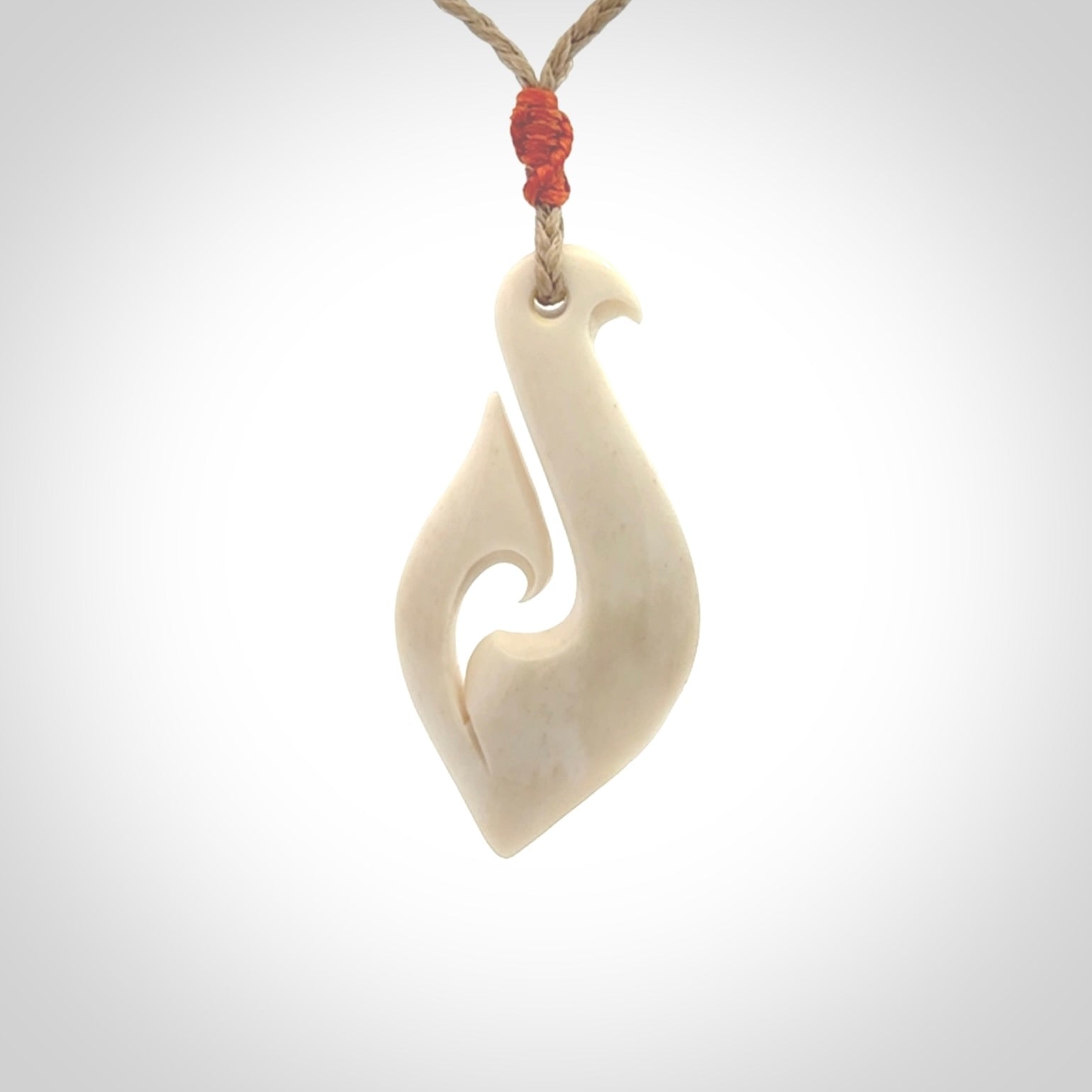 Hand carved bone hook pendant hand made by Peter Mitchell in New Zealand. This bone hook is provided with an adjustable Kalahari cord and packaged in a woven kete pouch. Free delivery worldwide.