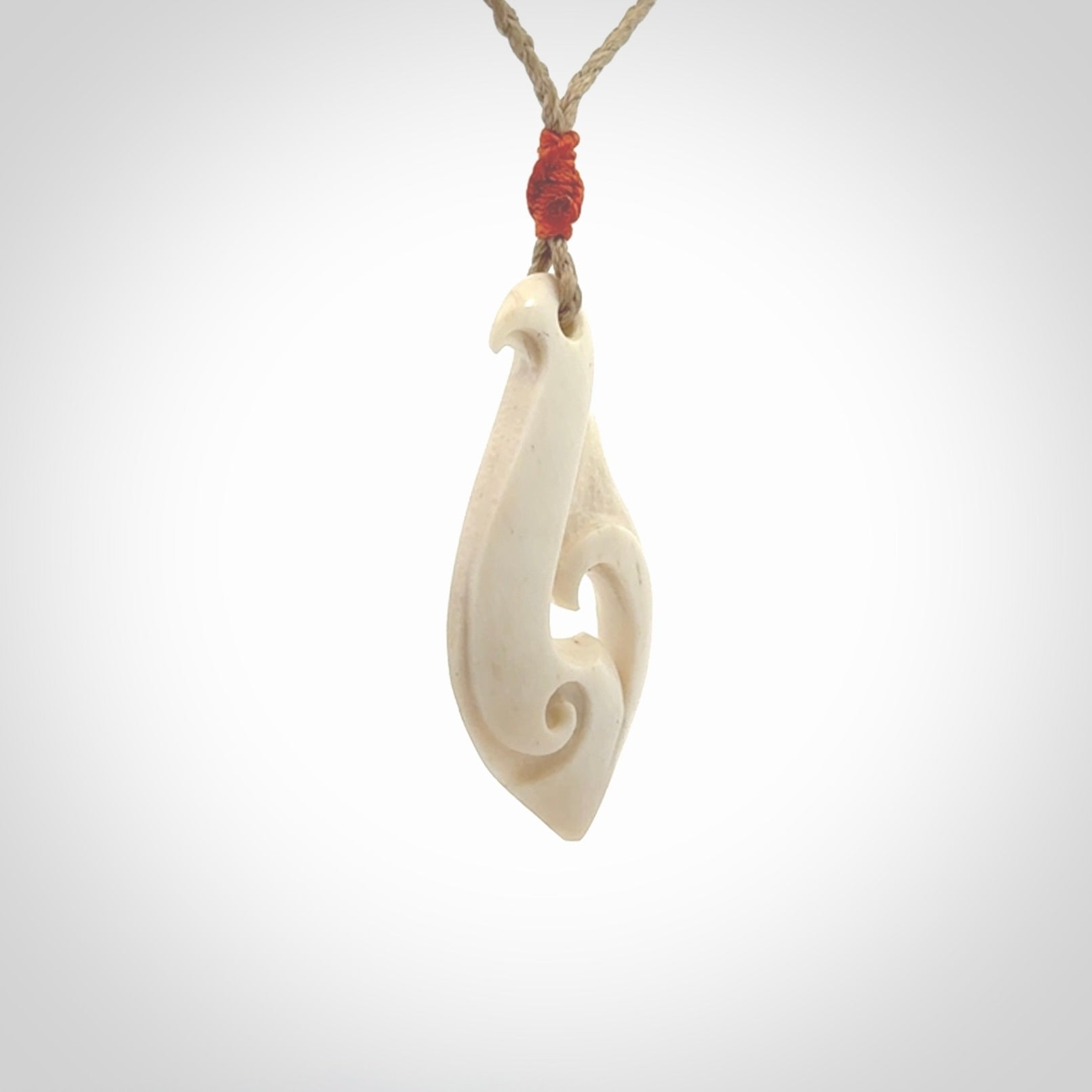 Hand carved bone hook pendant hand made by Peter Mitchell in New Zealand. This bone hook is provided with an adjustable Kalahari cord and packaged in a woven kete pouch. Free delivery worldwide.
