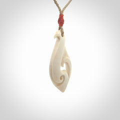Hand carved bone hook pendant hand made by Peter Mitchell in New Zealand. This bone hook is provided with an adjustable Kalahari cord and packaged in a woven kete pouch. Free delivery worldwide.