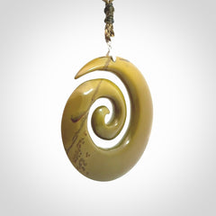 This picture shows a large hand-carved koru. It is carved from New Zealand flower jade and is suspended from an adjustable cord.