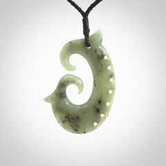 This picture shows a large hand-carved contemporary koru pendant. It is carved from New Zealand Kokopu jade and is suspended from a hand-plaited, black cord.