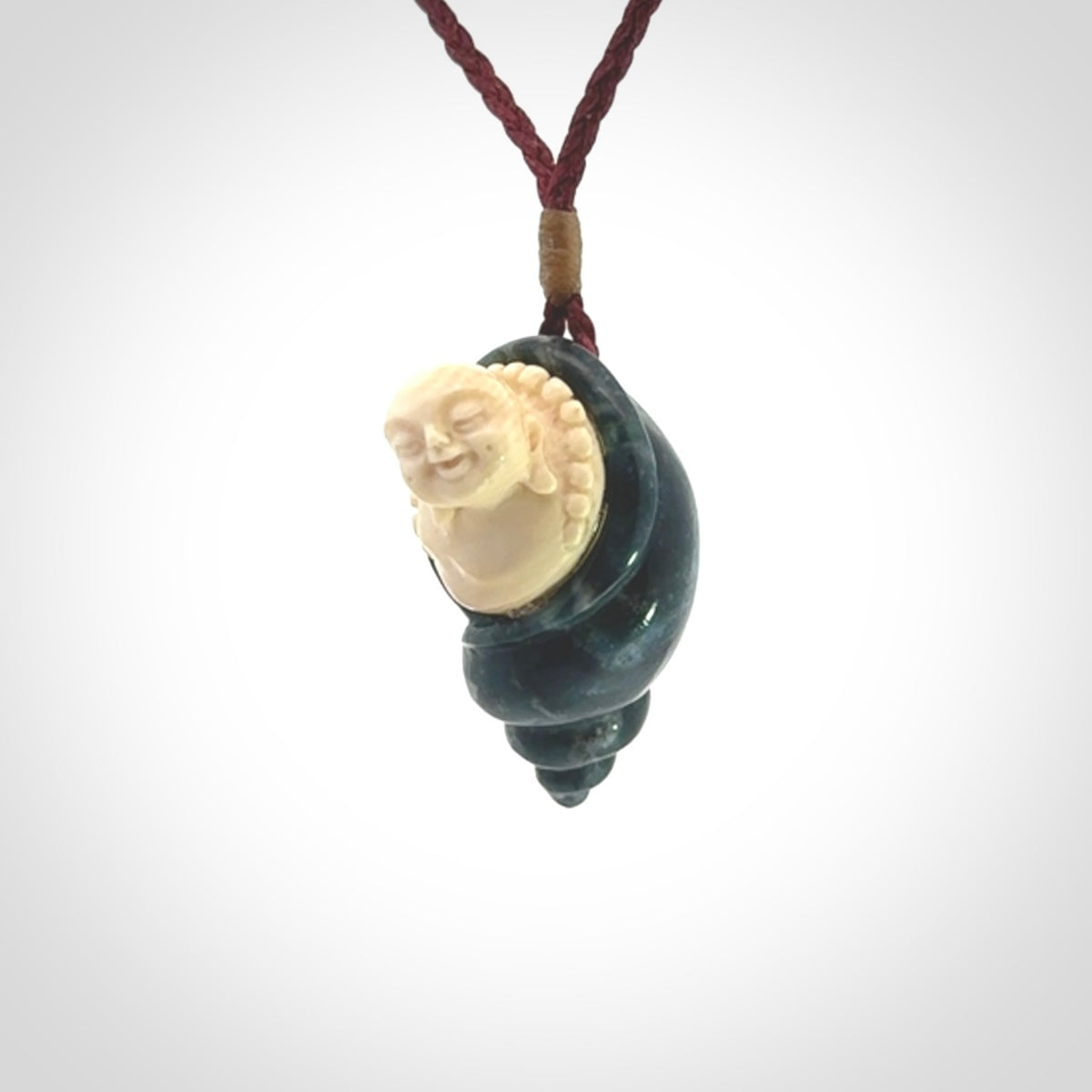 This photo shows a Buddha pendant hand carved in Woolly Mammoth Tusk with Moss Agate. It is provided with an adjustable plum cord.