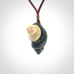 This photo shows a Buddha pendant hand carved in Woolly Mammoth Tusk with Moss Agate. It is provided with an adjustable plum cord.