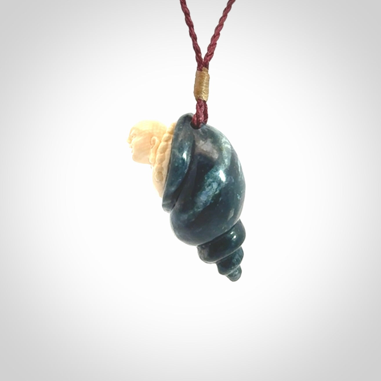 This photo shows a Buddha pendant hand carved in Woolly Mammoth Tusk with Moss Agate. It is provided with an adjustable plum cord.