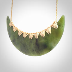 This picture shows a hand carved jade contemporary half-shield pendant. It is a semi-transluscent green colour. The cord is hand plaited and adjustable so that you can position the pendant where it suits you best.