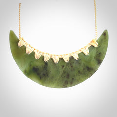 This picture shows a hand carved jade contemporary half-shield pendant. It is a semi-transluscent green colour. The cord is hand plaited and adjustable so that you can position the pendant where it suits you best.