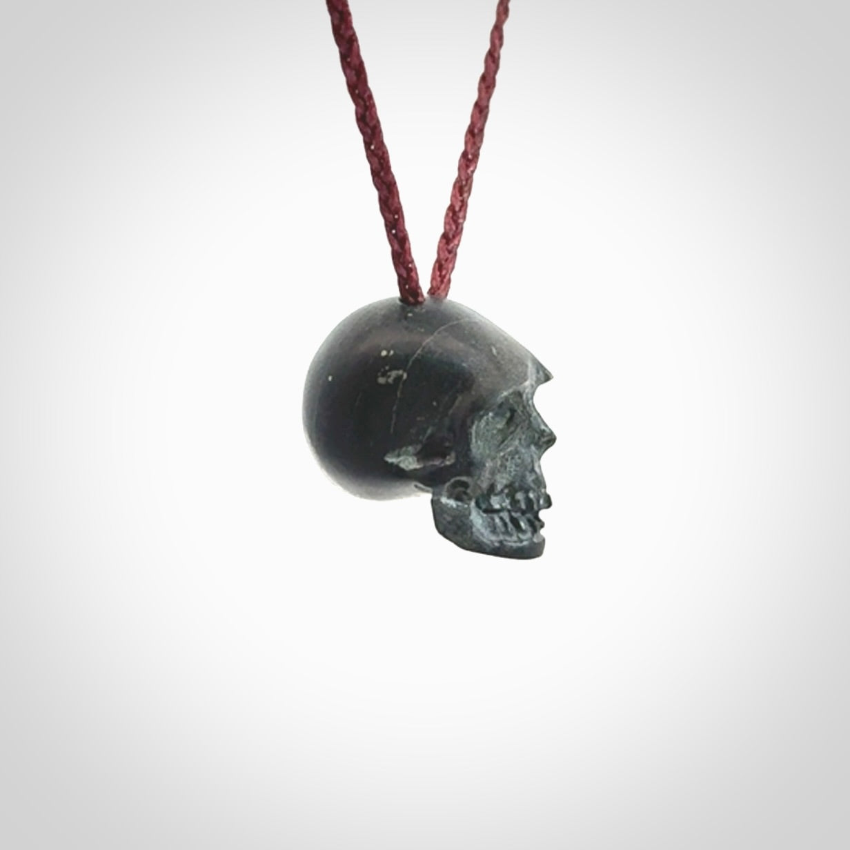 This picture shows a small Black Obsidian stone skull pendant that we have hand carved. It is polished to a soft shine and is a very striking piece. Provided with an adjustable plum cord.