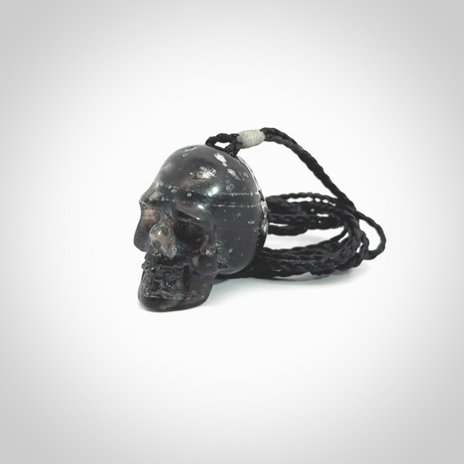 This picture shows a medium sized Snowflake Obsidian stone skull pendant that we have hand carved. It is polished to a soft shine and is a very striking piece. Provided with an adjustable black cord.