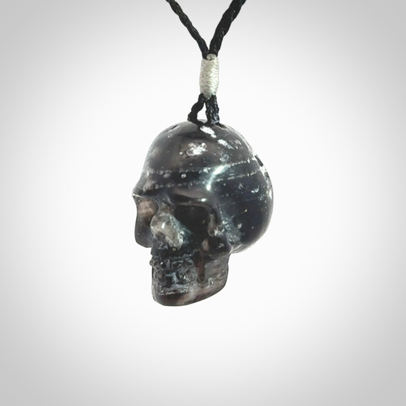 This picture shows a medium sized Snowflake Obsidian stone skull pendant that we have hand carved. It is polished to a soft shine and is a very striking piece. Provided with an adjustable black cord.