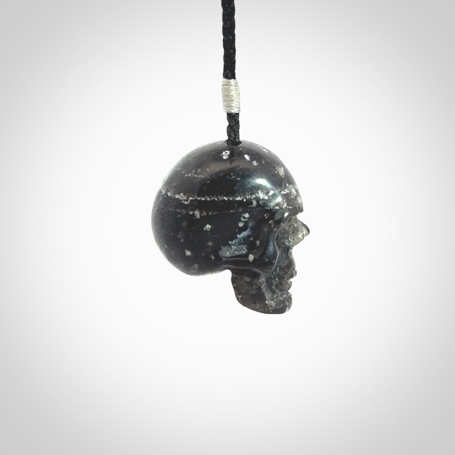 This picture shows a medium sized Snowflake Obsidian stone skull pendant that we have hand carved. It is polished to a soft shine and is a very striking piece. Provided with an adjustable black cord.