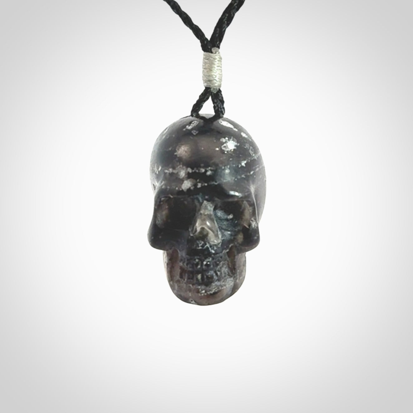 This picture shows a medium sized Snowflake Obsidian stone skull pendant that we have hand carved. It is polished to a soft shine and is a very striking piece. Provided with an adjustable black cord.