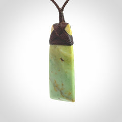 Hand carved from a lovely piece of local New Zealand flower Jade. We have suspended this from a 4-plait brown cord which can be adjusted with a couple of slip knots and brown binding.
