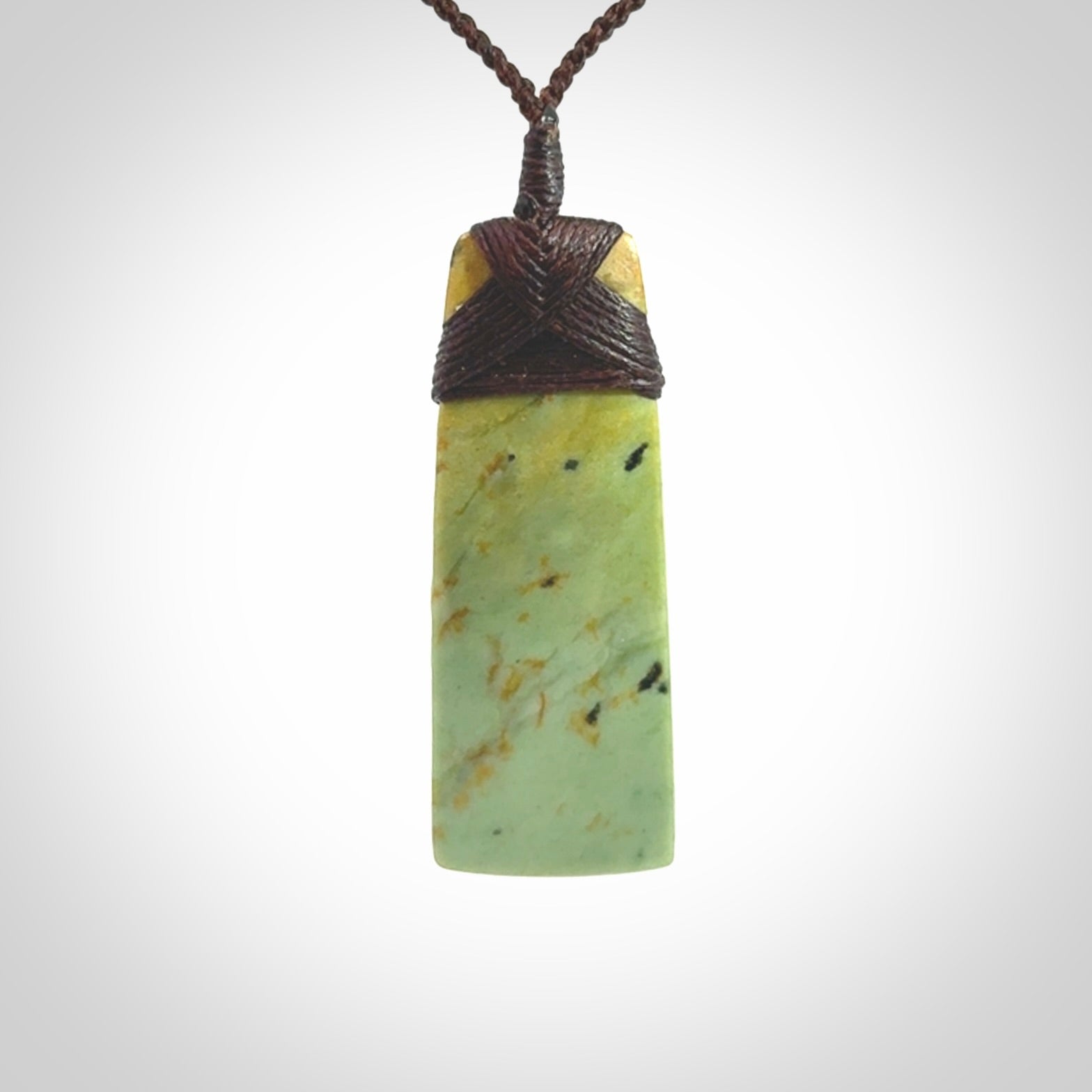 Hand carved from a lovely piece of local New Zealand flower Jade. We have suspended this from a 4-plait brown cord which can be adjusted with a couple of slip knots and brown binding.