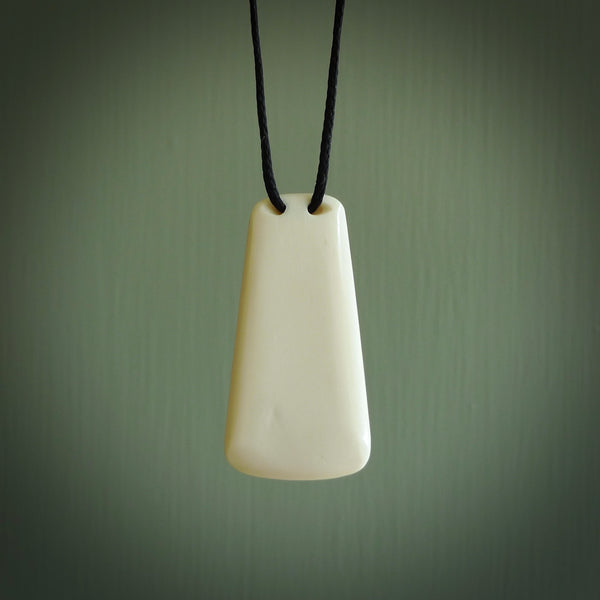 A hand carved unbound bone toki pendant. The cord is a black colour and is adjustable. Medium and large, hand made toki necklaces by New Zealand artist Kerry Thompson. One off work of art to wear.
