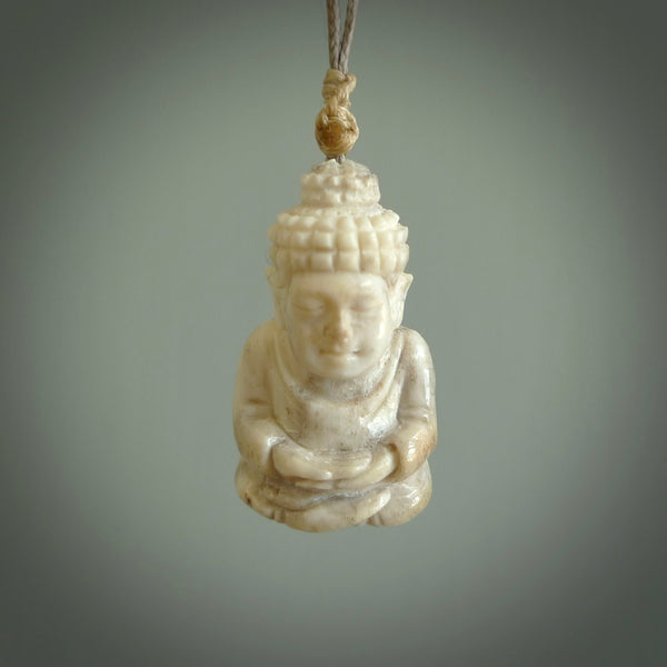 This photo shows a praying Buddha pendant hand carved in deer antler and woolly mammoth tusk. It is provided with a plaited cord necklace which is length adjustable. Your choice of either material. Delivered in a woven kete pouch. 